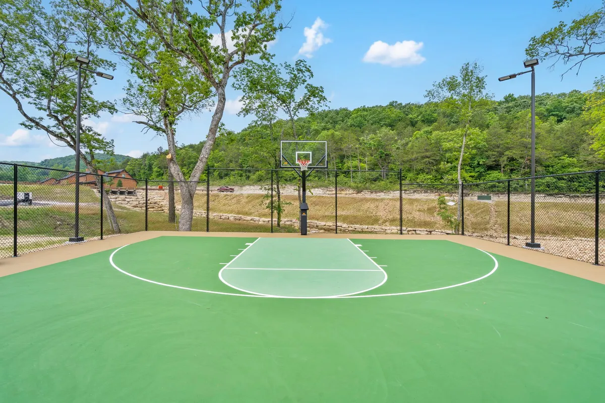 An energetic basketball court nestled among trees with a clear mountain view, featuring a basketball hoop and space for games. The atmosphere is lively—perfect for friendly matches and family tournaments.